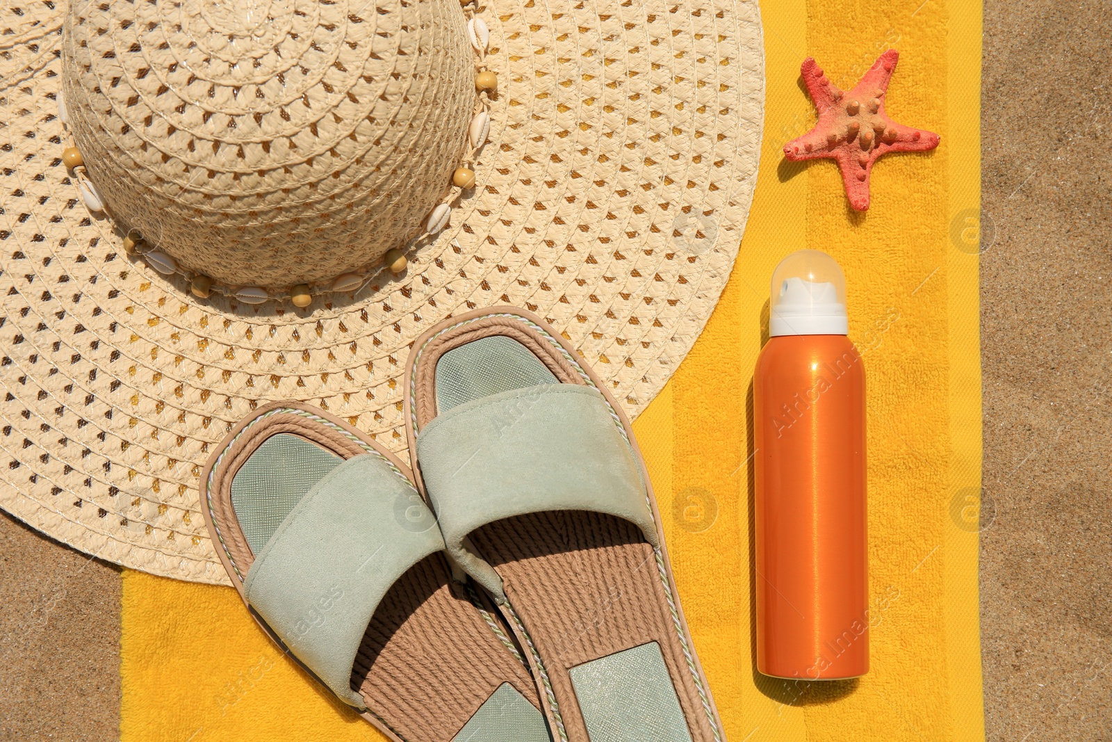 Photo of Sunscreen, starfish and beach accessories on sand, top view. Sun protection care