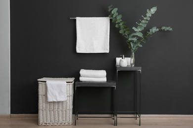 Photo of Clean soft towels on stand near black wall