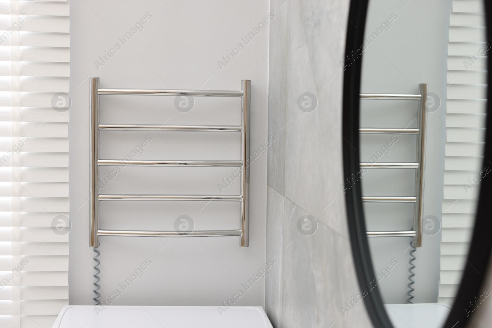 Photo of Modern heated towel rail on wall in bathroom