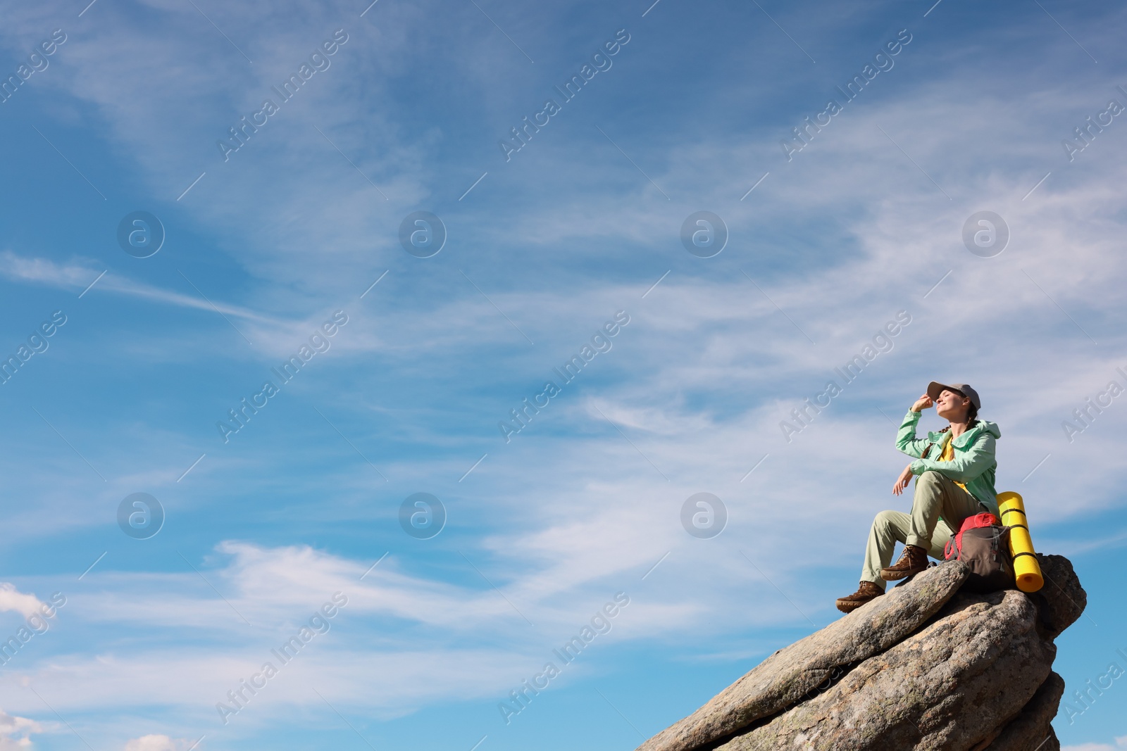 Photo of Young woman with backpack on rocky peak in mountains. Space for text