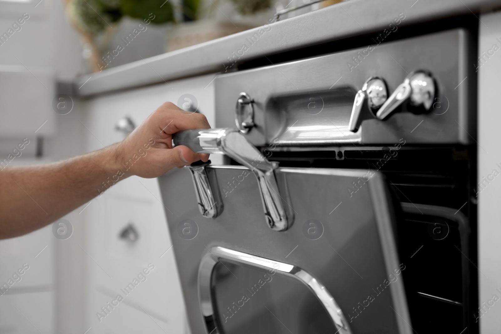 Photo of Man using modern oven in kitchen, closeup