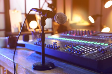 Photo of Microphone near professional mixing console on table in radio studio