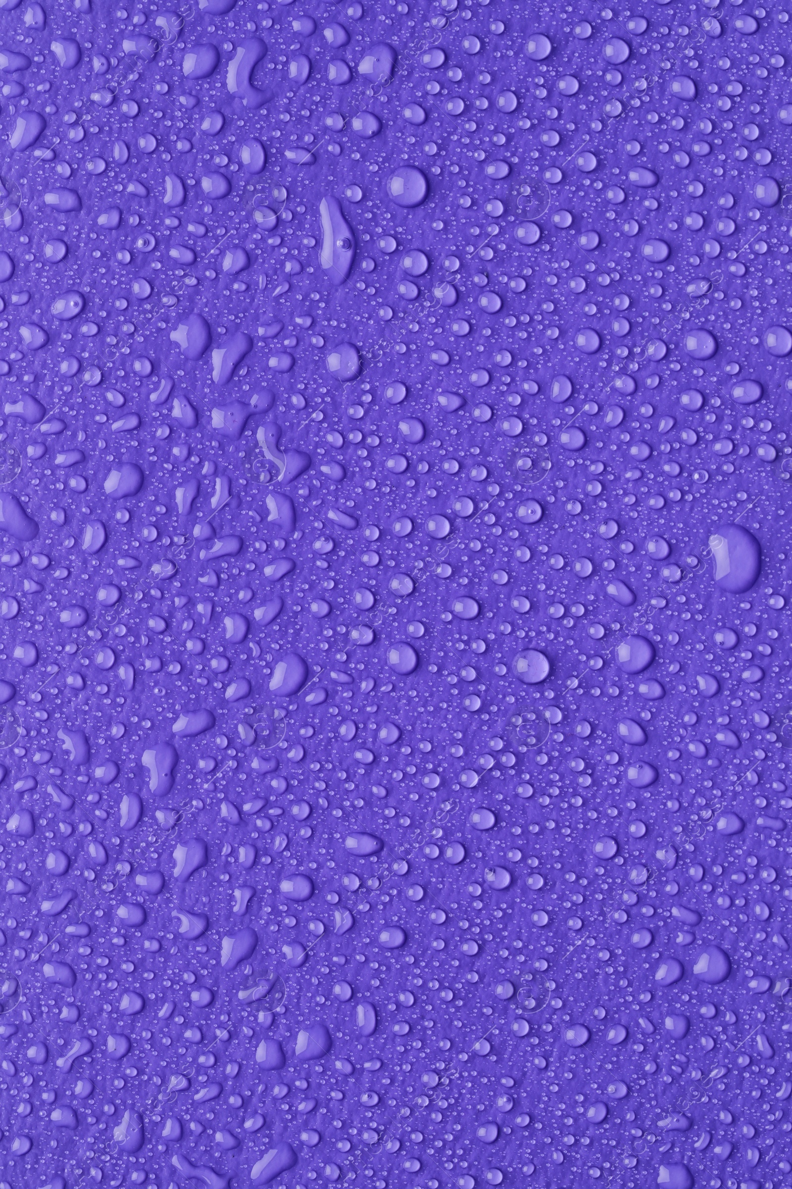 Photo of Water drops on lilac background, top view