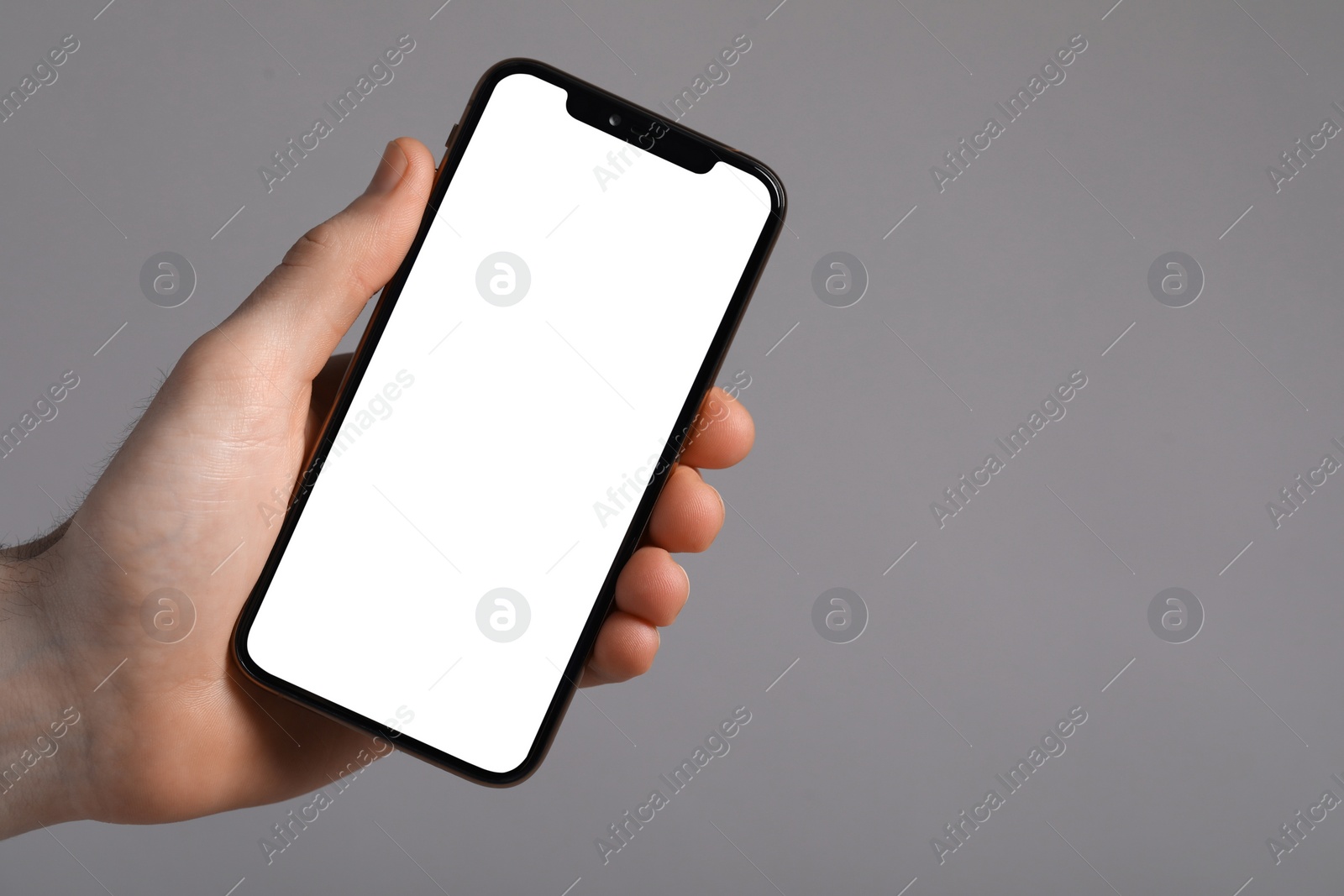 Photo of Man holding smartphone with blank screen on light grey background, closeup. Mockup for design