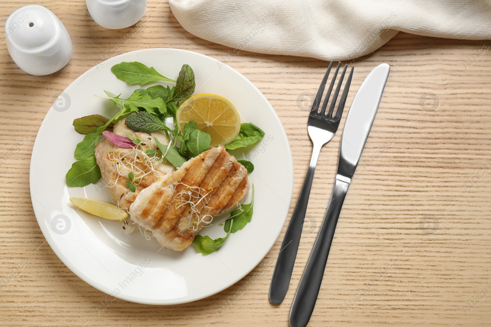 Photo of Tasty grilled fish served on wooden table, flat lay