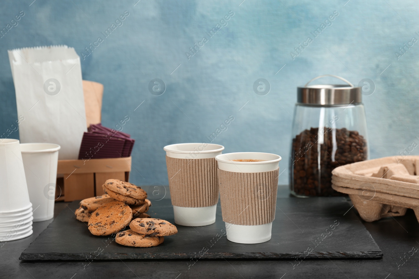 Photo of Composition with aromatic hot coffee in paper cups and cookies on table