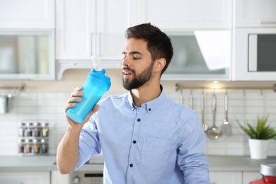 Young man drinking protein shake in kitchen