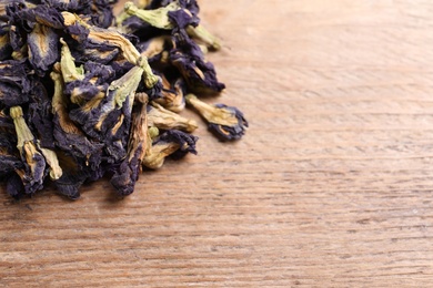 Photo of Pile of dry organic blue Anchan on wooden table, closeup with space for text. Herbal tea