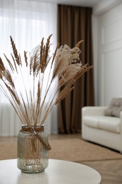 Photo of Fluffy reed plumes on white table in living room interior