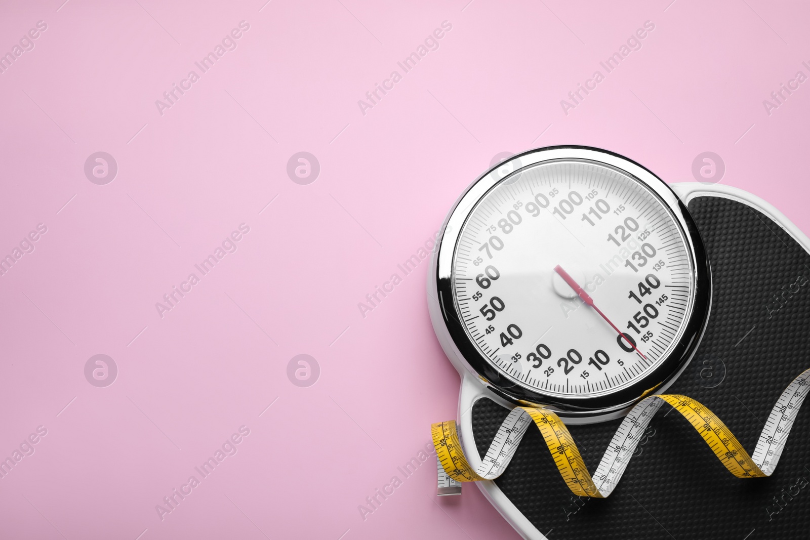 Photo of Scales and measuring tape on pink background, top view. Space for text