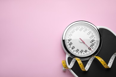 Scales and measuring tape on pink background, top view. Space for text