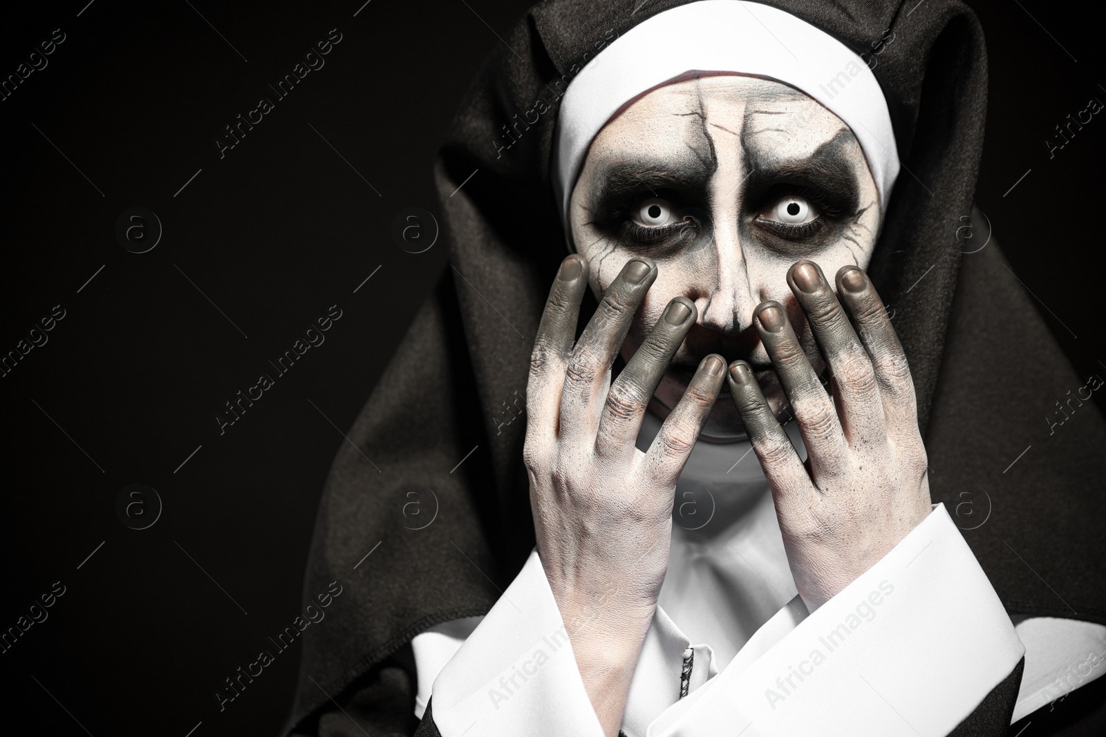 Photo of Portrait of scary devilish nun on black background, space for text. Halloween party look