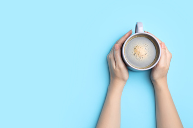 Photo of Woman with cup of coffee on light blue background, top view. Space for text