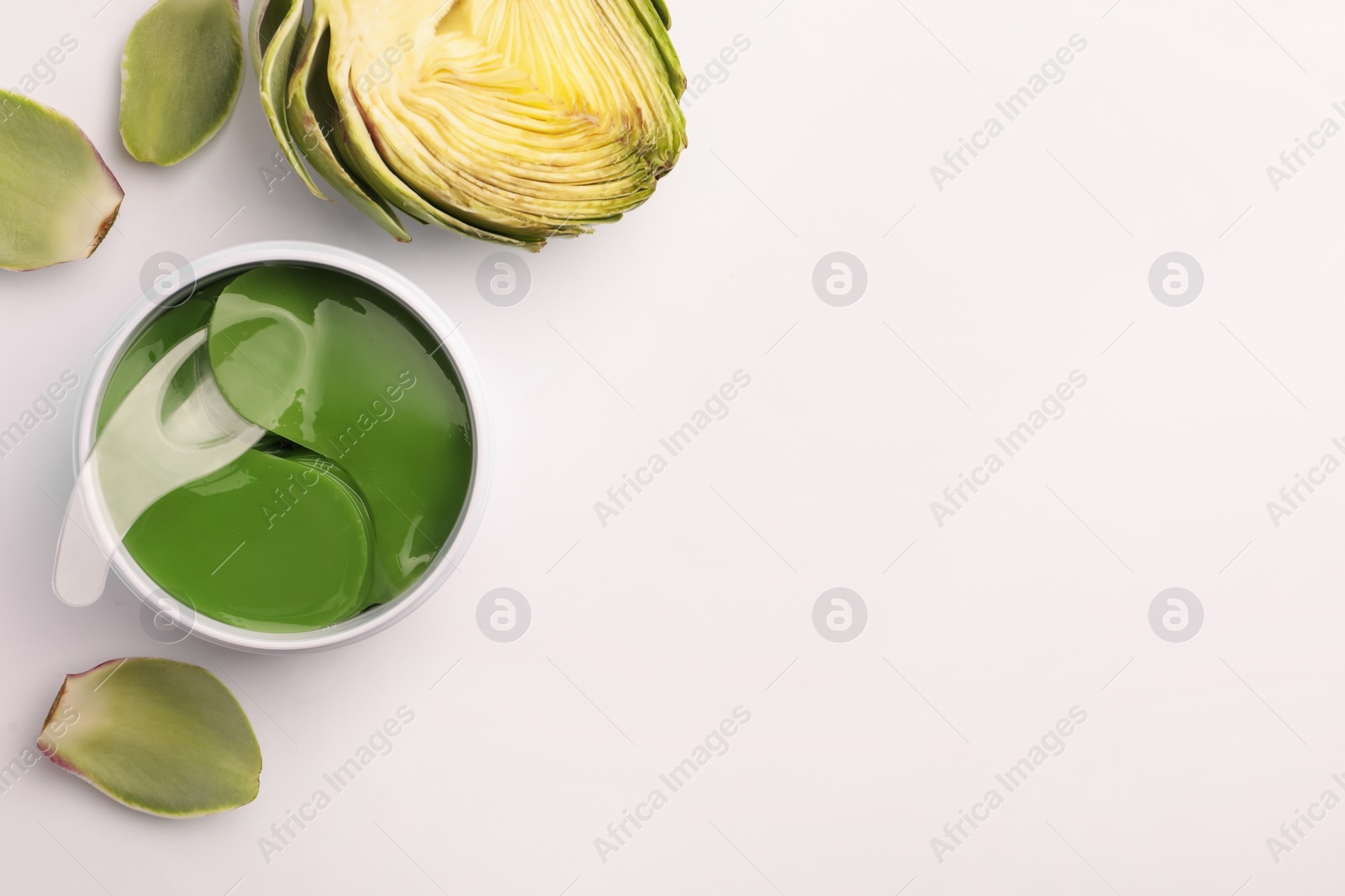 Photo of Package of under eye patches and artichokes on white background, top view. Cosmetic product