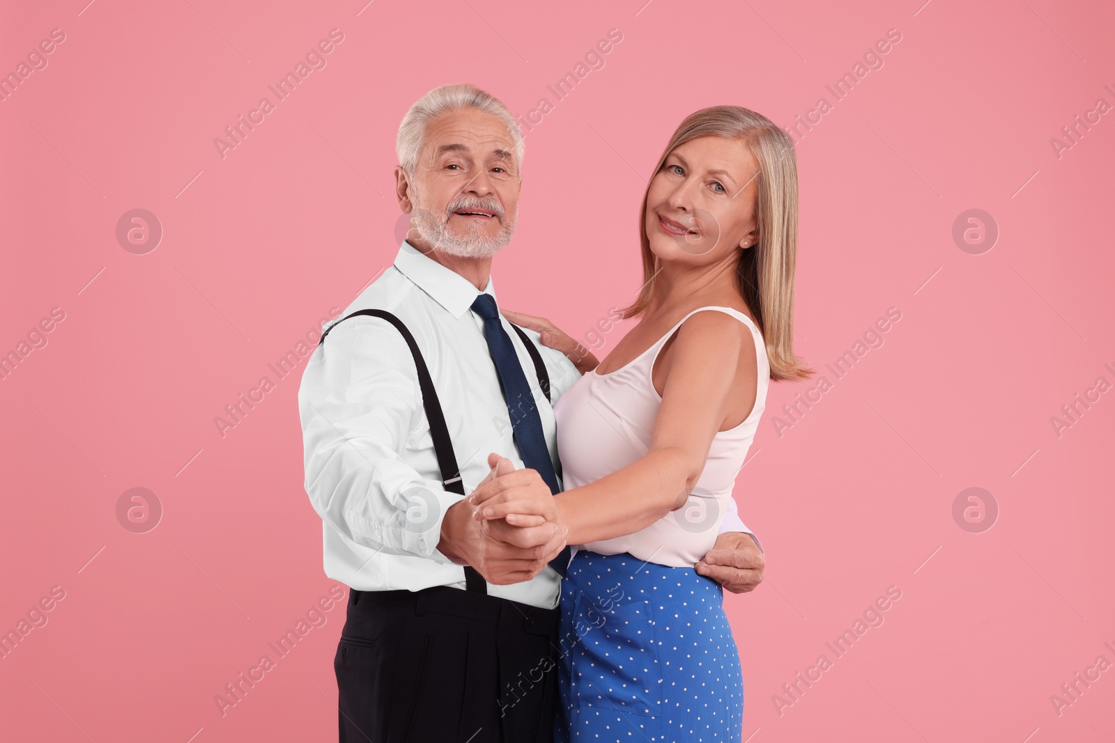 Photo of Senior couple dancing together on pink background