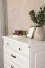 Modern chest of drawers with decor near beige wall