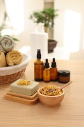 Photo of Soap bar, dry flowers, bottles of essential oils, jar with cream and towels on wooden table indoors. Spa time