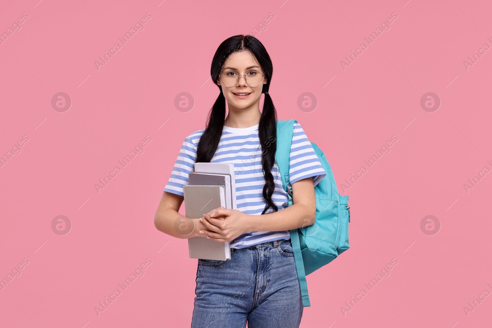 Photo of Smiling student with books and backpack on pink background