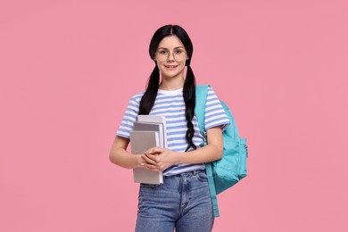 Smiling student with books and backpack on pink background