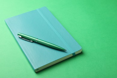 New stylish planner with hard cover and pen on green background