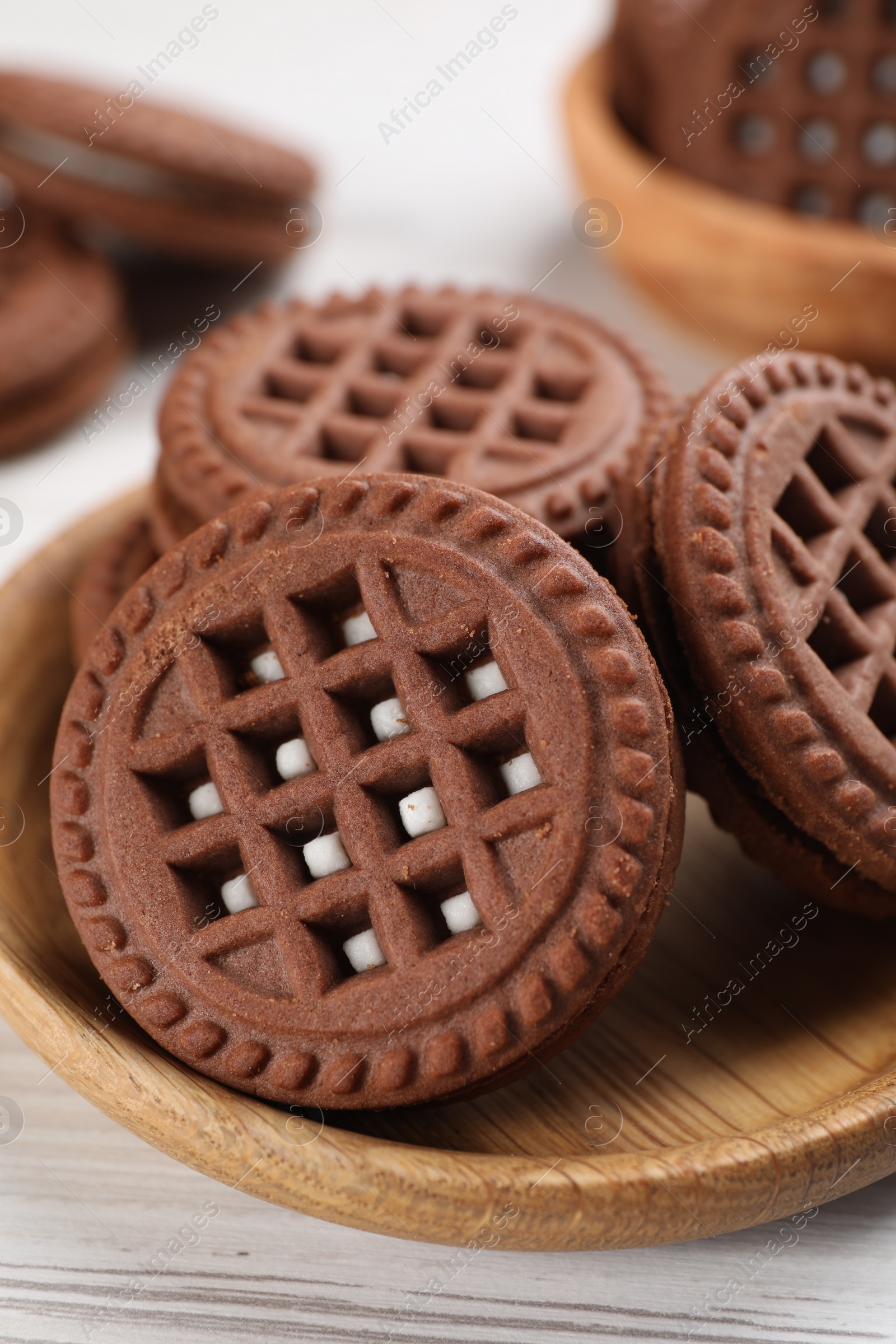 Photo of Tasty chocolate sandwich cookies with cream on white wooden table, closeup