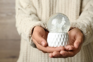 Woman holding snow globe on blurred background, closeup