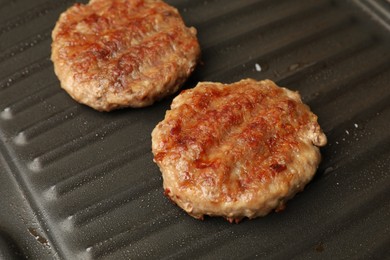 Photo of Tasty hamburger patties on grill pan, closeup