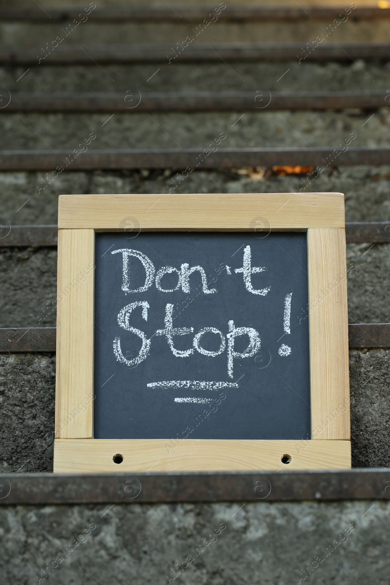 Photo of Chalkboard with phrase Don't Stop on stone stairs outdoors
