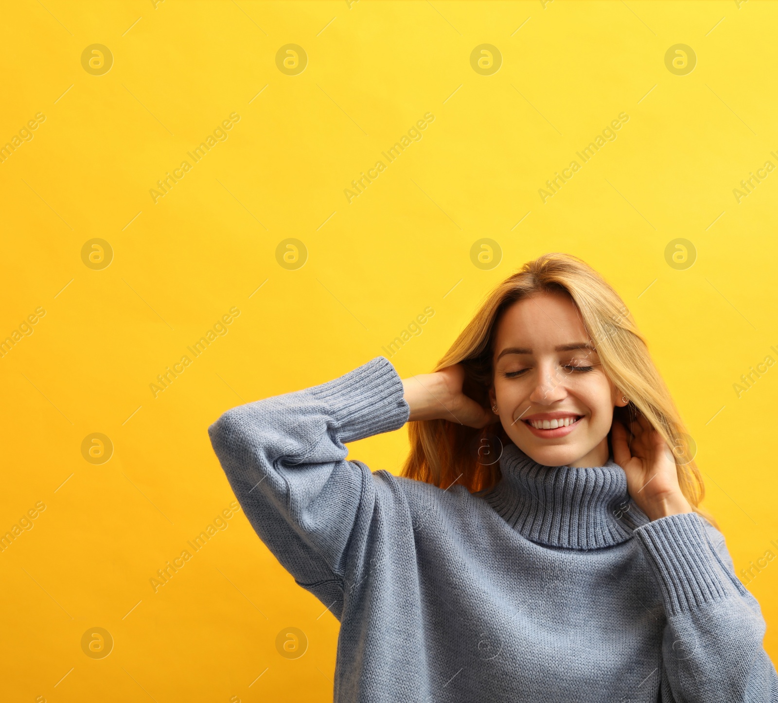 Photo of Beautiful young woman wearing knitted sweater on yellow background. Space for text