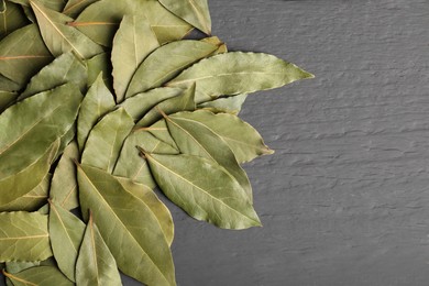 Photo of Pile of aromatic bay leaves on gray wooden table, top view. Space for text