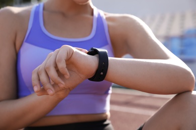 Photo of Woman checking fitness tracker after training at stadium, closeup
