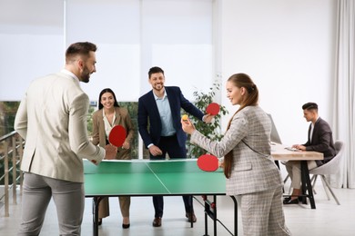 Photo of Business people playing ping pong in office