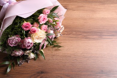 Photo of Beautiful bouquet with roses on wooden table. Space for text