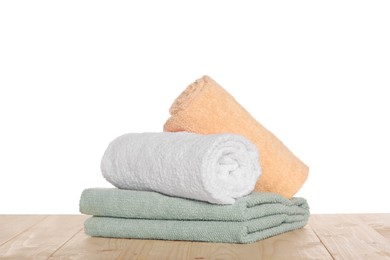 Soft colorful terry towels on wooden table against white background