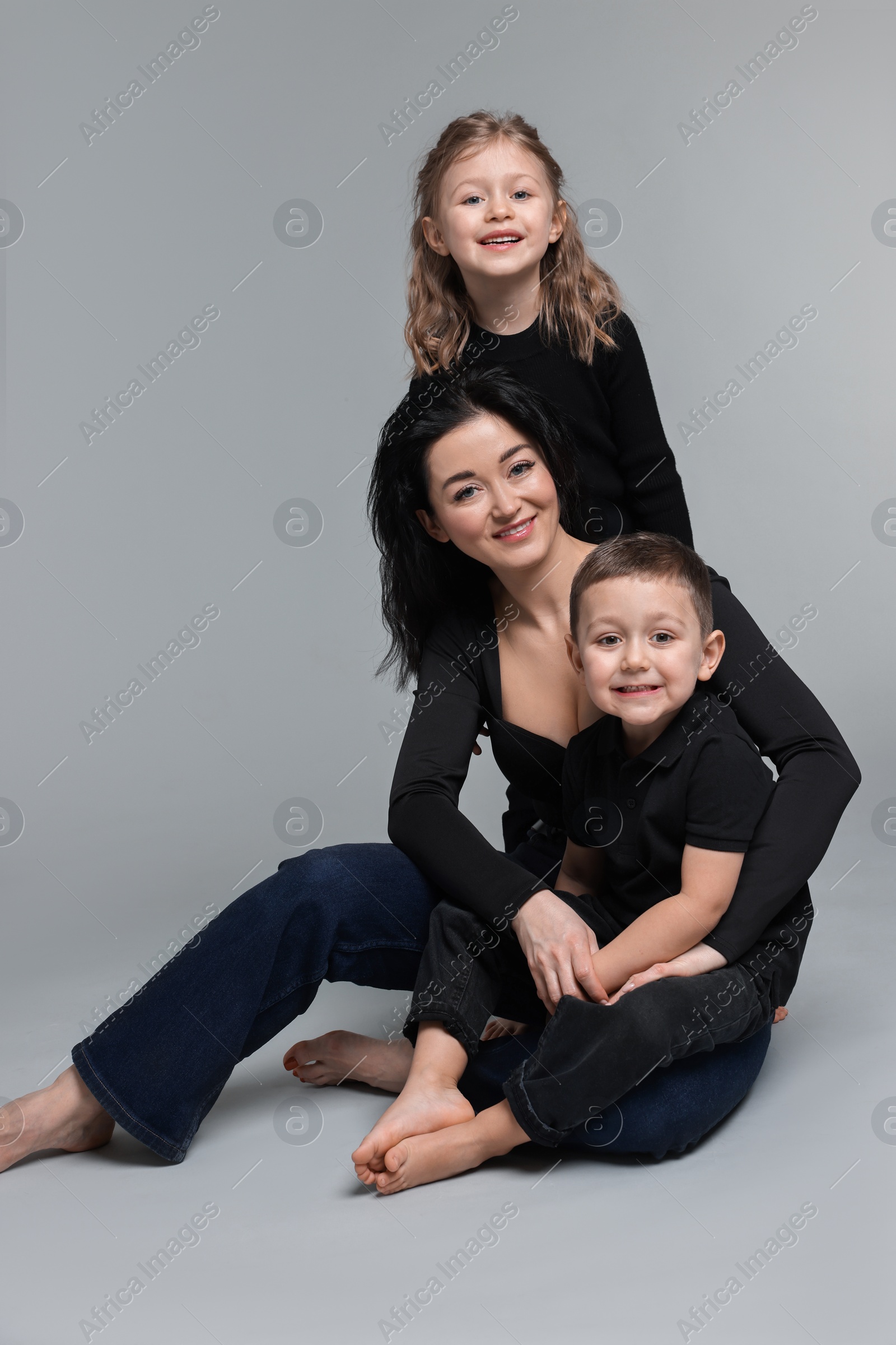 Photo of Little children with their mother on grey background