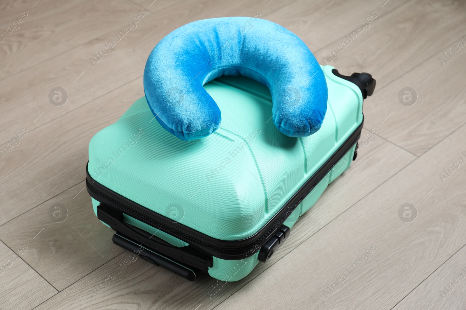 Photo of Turquoise travel pillow and suitcase on floor