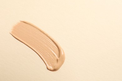 Photo of Smear of skin foundation on beige background, top view. Space for text