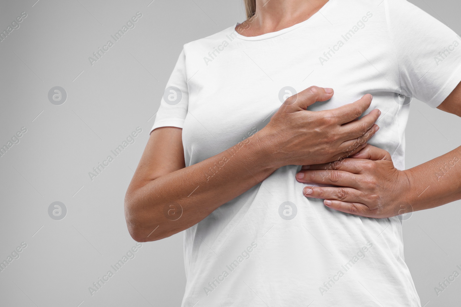 Photo of Woman doing breast self-examination on light grey background, closeup. Space for text