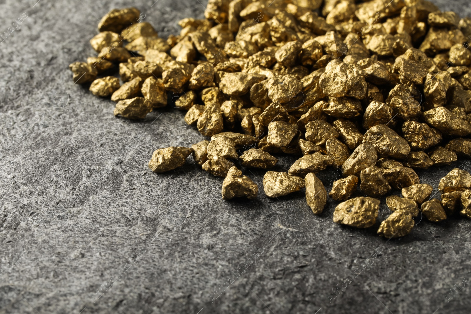 Photo of Pile of gold nuggets on grey table, space for text