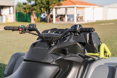 Photo of Modern quad bike in field near house on sunny day, closeup