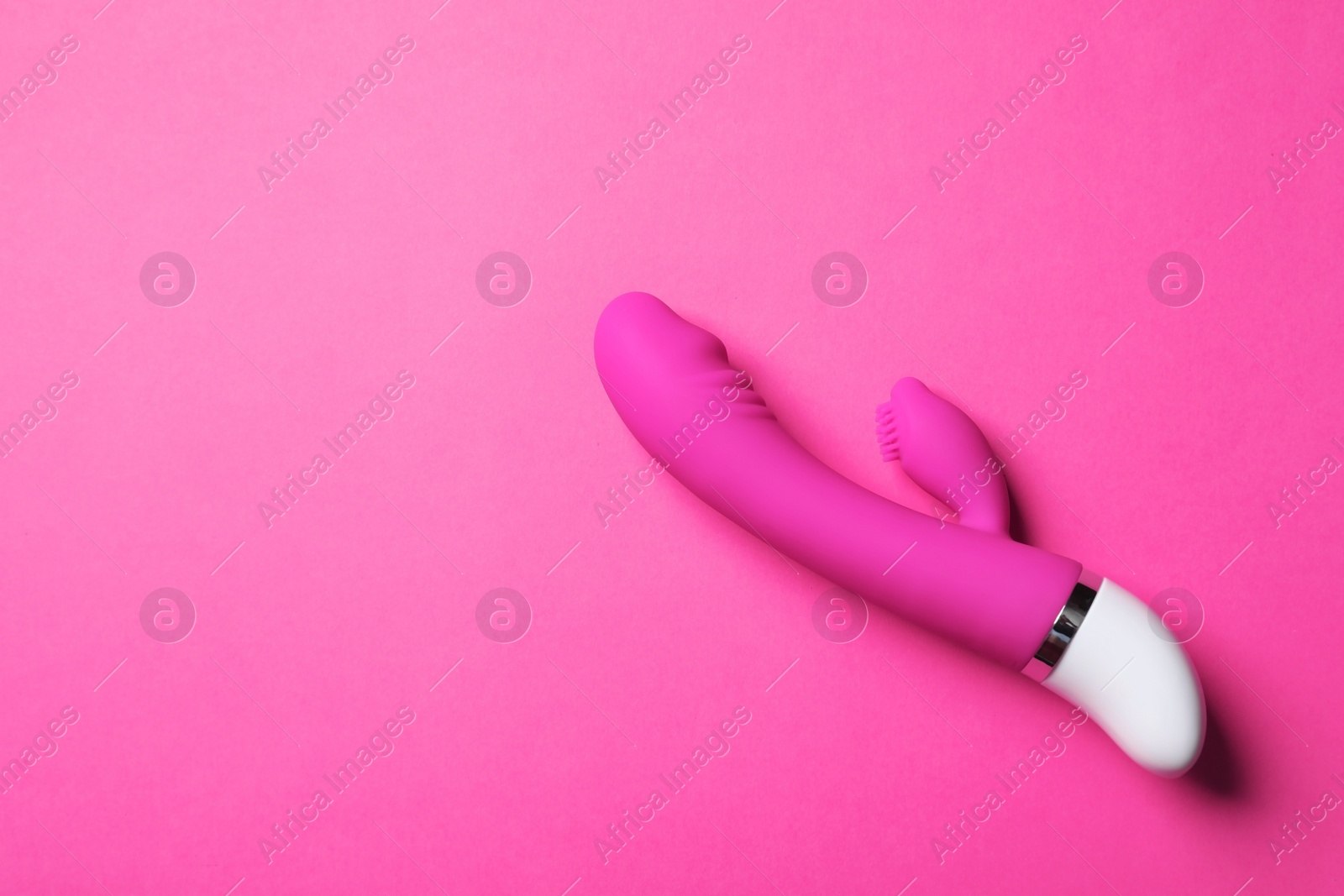 Photo of Dildo on pink background, top view with space for text. Sex toy