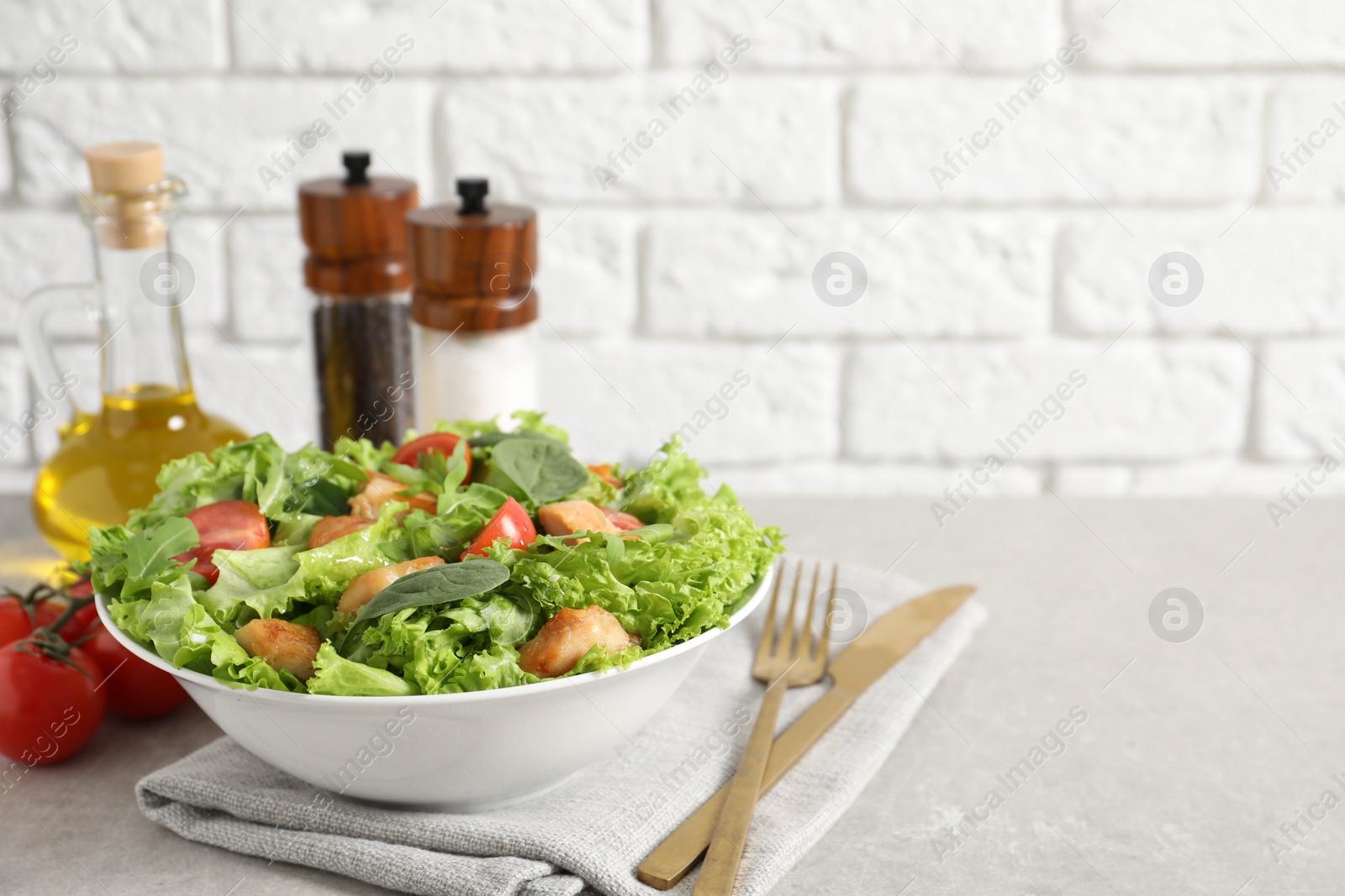 Photo of Delicious salad with chicken, cherry tomato and spinach served on light grey table, space for text