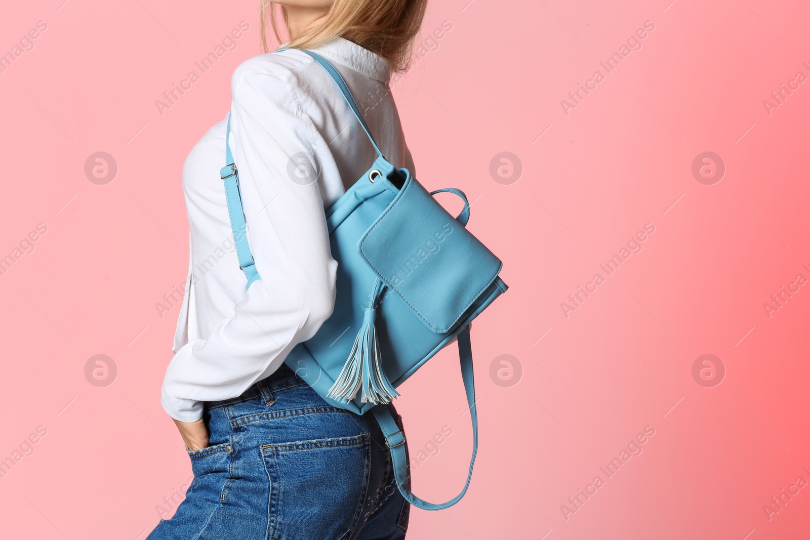 Photo of Fashionable woman with backpack on color background, closeup. Space for text