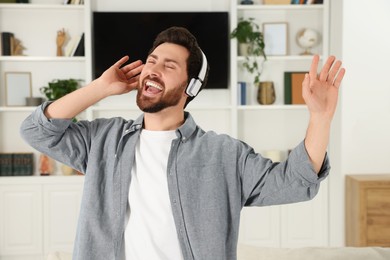 Photo of Emotional man dancing while listening music with headphones at home