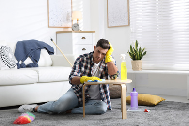 Photo of Lazy man procrastinating while cleaning at home