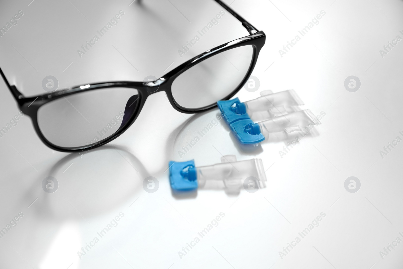 Photo of Single dose eye drops and glasses on white table