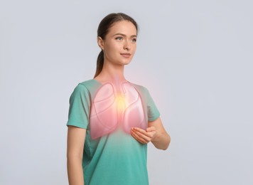 Young woman holding hand near chest with illustration of lungs on light grey background