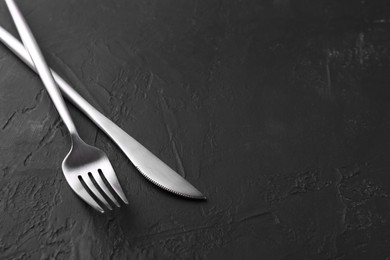 Photo of Beautiful cutlery set on black table. Space for text