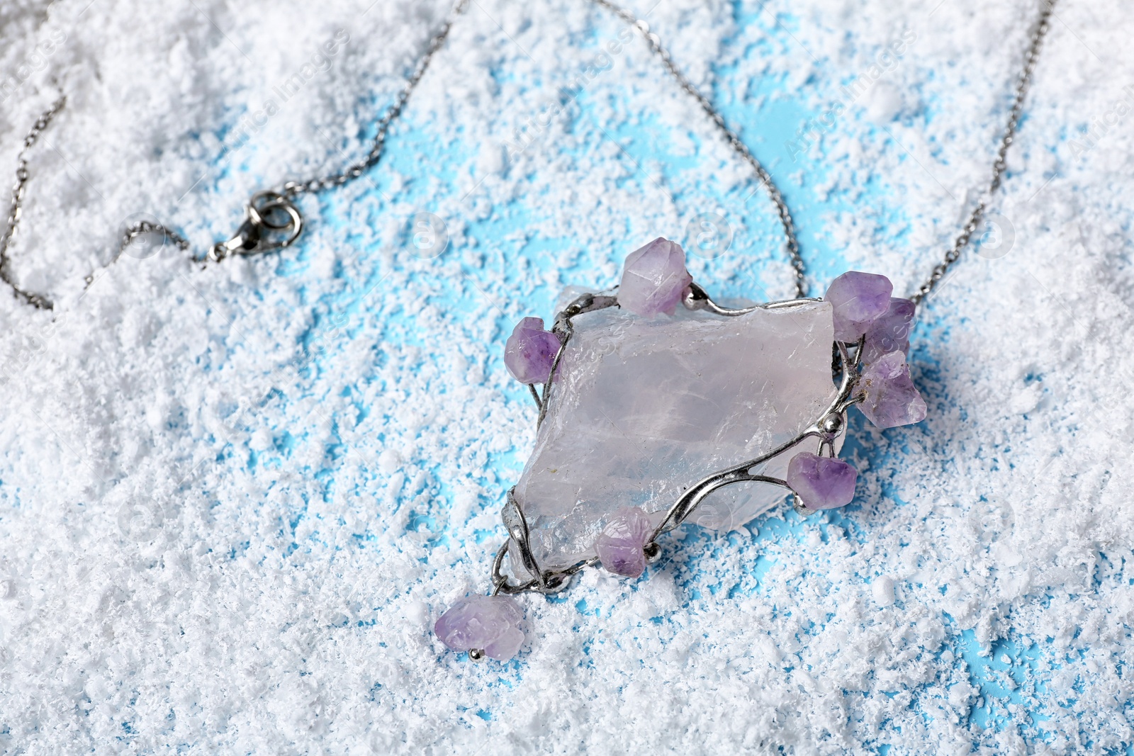 Photo of Beautiful silver pendent with pure quartz and amethyst gemstones on snow. Space for text