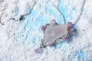 Beautiful silver pendent with pure quartz and amethyst gemstones on snow. Space for text